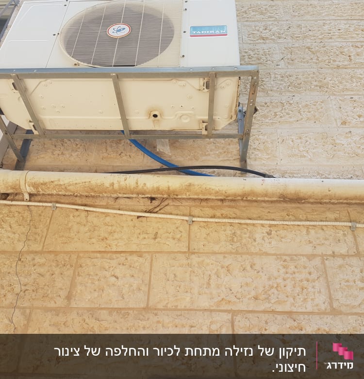 צינור מים לבן מחובר לקיר אבן
